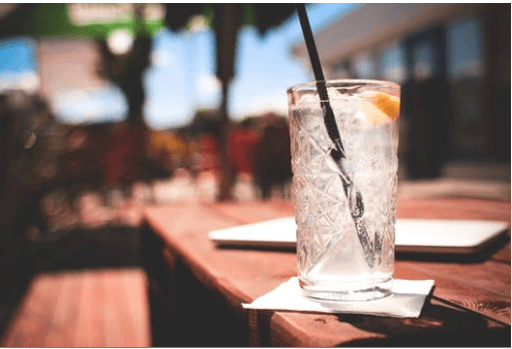 A drink of bubbly water with a lemon slice sitting on a bar.