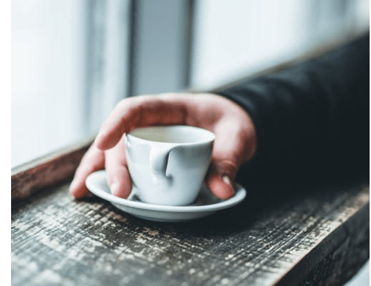 Photo of a hand holding an espresso cup.