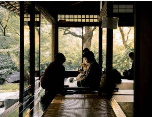 People in a Japanese garden sipping tea.