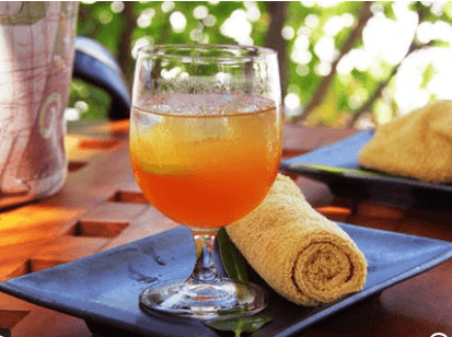 A picture of an ice tea with lemon in a large wine glass.