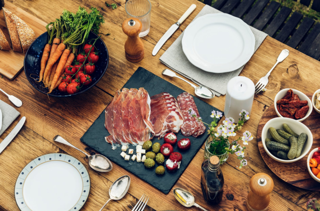 A table setting with meats and pickled foods.