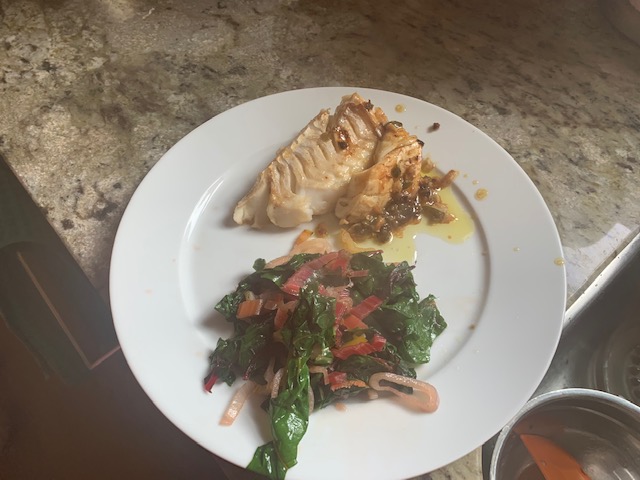 Picture of a white plate with fish and a chard side.