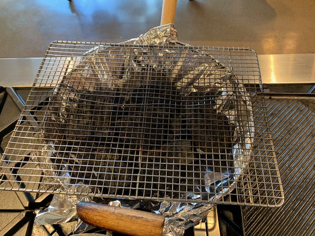 Photo of a homemade grill with a wok, aluminum foil, and a cooking rack.