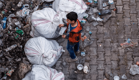 Photo of a kid surrounded by garbage.