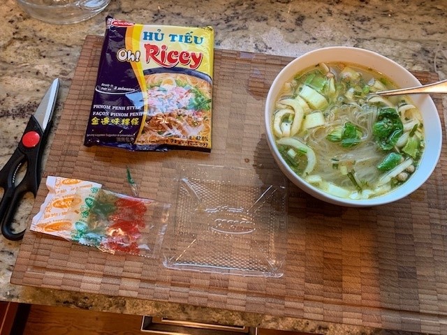 Photo of the package and bowl of the noodle soup. The broth is a light color, associated with fish broth.