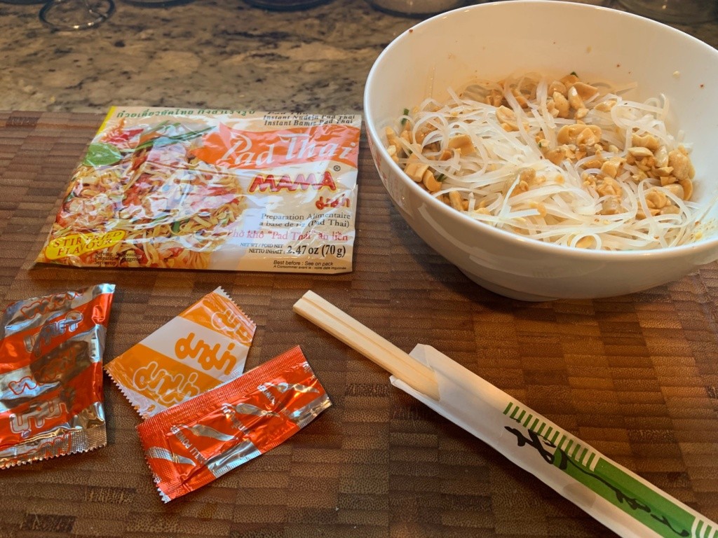 Photo of the noodle pack and contents, chop sticks, and a bowl of the noodles with peanuts.