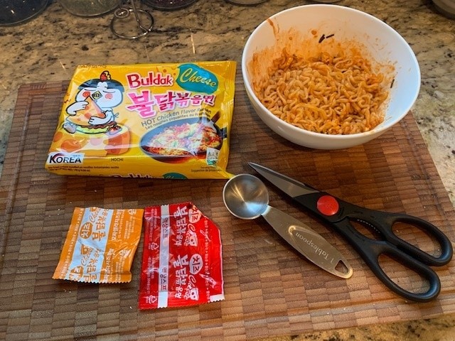 Photo of the noodle package, seasoning packets, bowl of cooked noodles a measuring spoon and kitchen shears.SamY