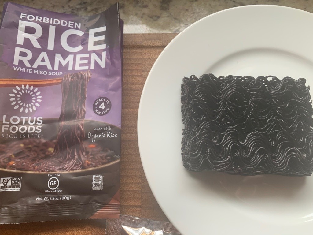 A plate with the black-purple, uncooked noodles and its packaging.