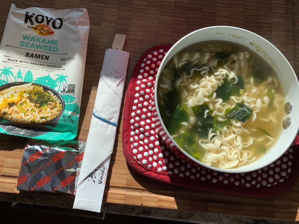 Photo of a pot of cooked noodles + soup with the packaging and chop sticks.