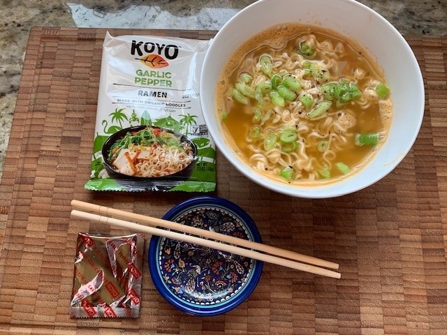 Photo of a ramen and soup bowl with the packaging and a small dish holding chop sticks.