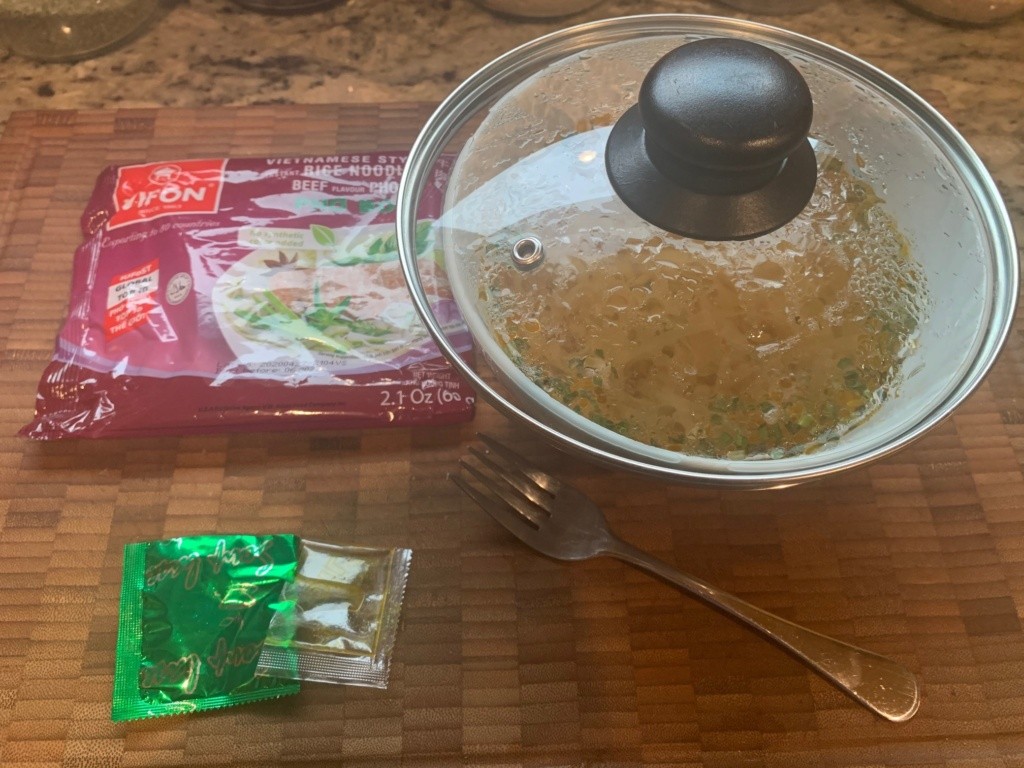 Image of the soup packaging, and a white bowl with the soup, lidded as it steams.