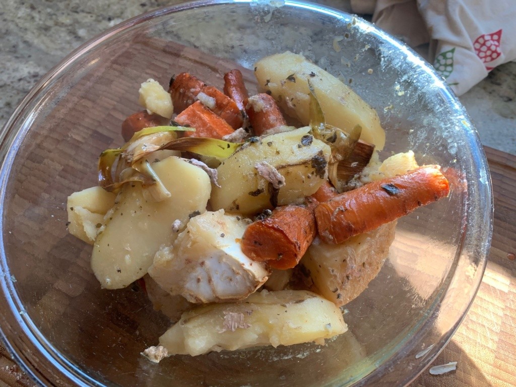 A clear bowl of the veggies just taken from the turkey baking pan. Sort of messy looking pile of celery root, carrots, cooked herbs and leeks, and potatoes.