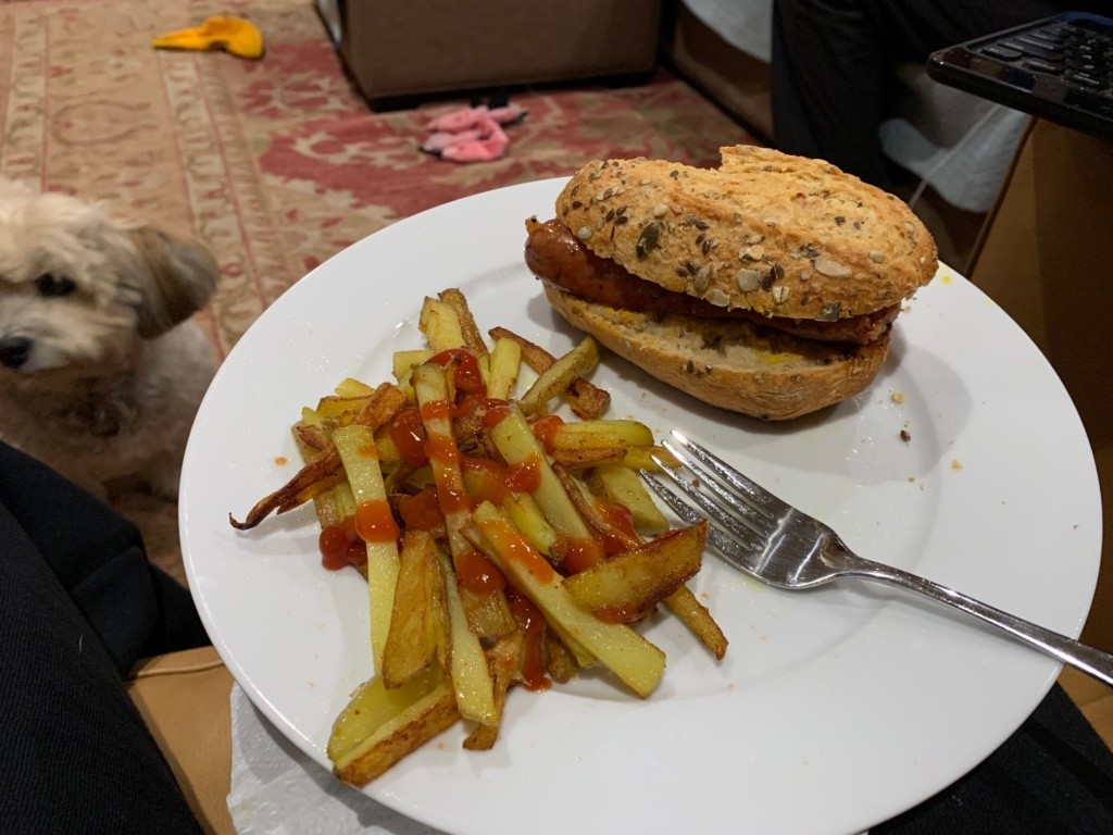 A photo of the potato carrot roll with a sausage, on a plate with fries.