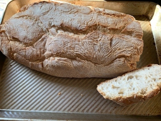 Picture of Andalusian loaf, on a baking sheet with the end cut of to show a light, withish interior.