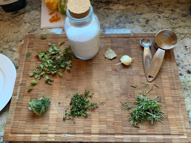 A picture of making a herb-salt with herbs and kosher salt on my cutting board.