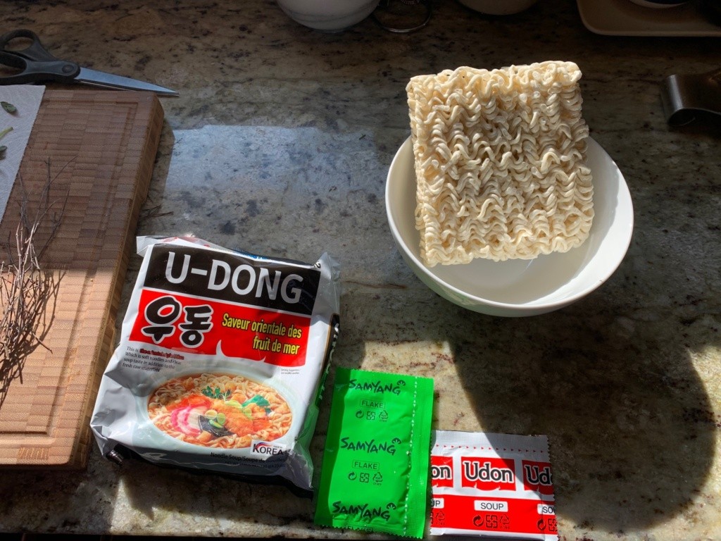 Photo of the packaging, a bowl showing the noodle puck, and the packets of broth and flavors.