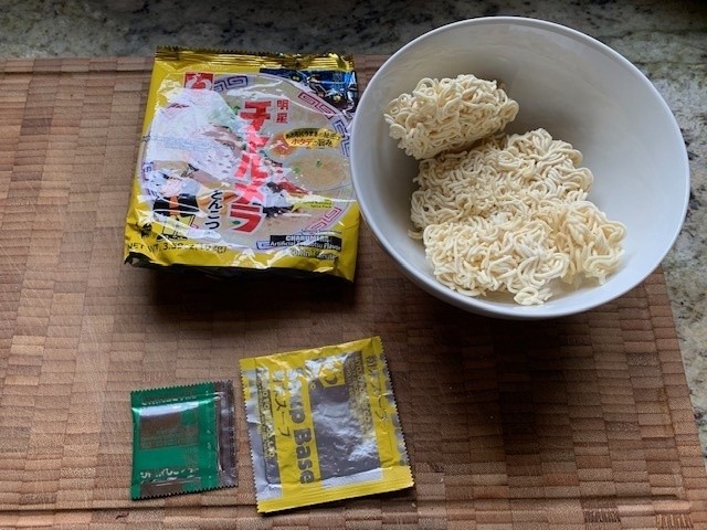 A picture of Myojo soup with a noodle pack in a bowl and two seasoning packets.