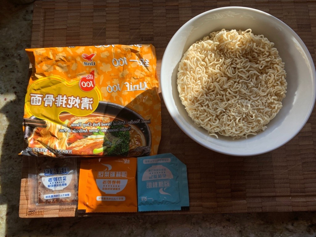 Photo of the packaging, a bowl showing the noodle puck, and the packets of broth and flavors.