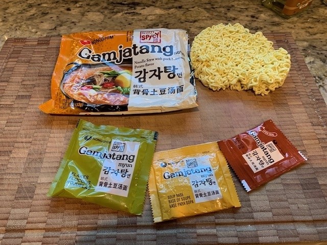 Photo of the Nongshim package contents of a noodle puck and three packets.