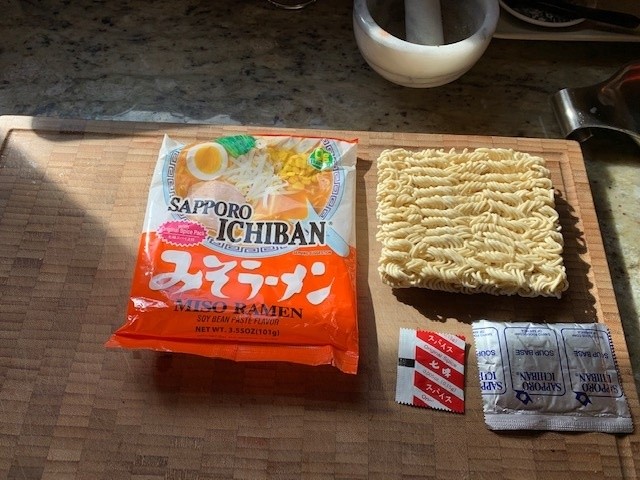 Picture of Sapporo package of a square tightly compressed noodle puck and two seasoning packets.