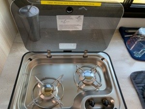 A closeup of the stove top showing two burners and the lid that also operates as a backsplash.