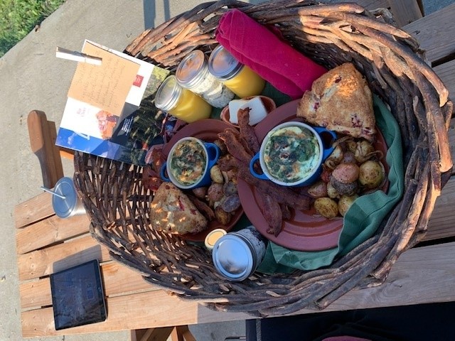 A basket with all the breakfast food sits on the picnic table, along with my ipad.